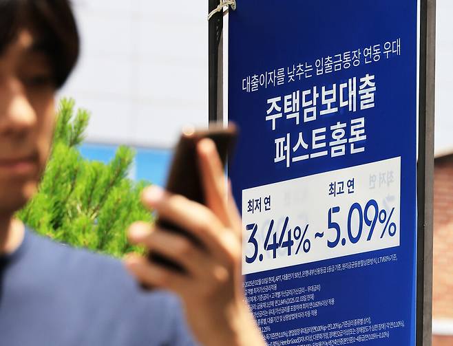 15일 한 시민이 서울 시내 은행 앞 대출 홍보물을 지나고 있다. 연합뉴스