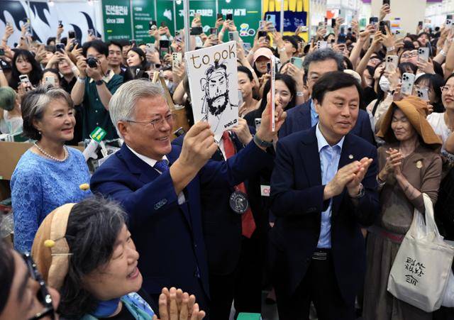 문재인 전 대통령과 부인 김정숙 여사가 18일 서울 강남구 삼성동 코엑스에서 열린 2025 서울국제도서전 평산책방 부스를 찾아 괴산로컬잡지 툭의 임꺽정 특집호를 들어 보이고 있다. 뉴스1