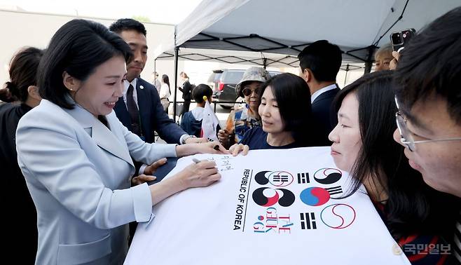 G7 정상회의에 참석하는 이재명 대통령과 함께 캐나다를 방문한 김혜경 여사가 17일(현지시간) 캘거리 한인회관에서 환영나온 주민들의 요청에 티셔츠에 서명하고 있다. 캘거리=김지훈 기자