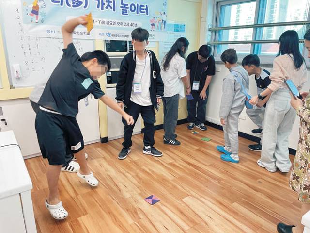 지난해 세화종합사회복지관의 ‘다(多)가치 놀이터’ 사업을 통해 한국 전통놀이에 대해 배운 이주배경아동들이 직접 만든 딱지로 딱지치기를 하고 있다.  초록우산 제공