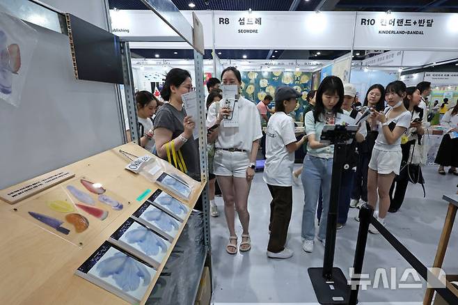[서울=뉴시스] 박진희 기자 = '2025 서울국제도서전'이 열린 18일 서울 강남구 코엑스 행사장을 찾은 관람객들이 책갈피 굿즈를 살펴보고 있다. 올해 도서전에는 한국을 포함해 17개국의 530여 개 출판사와 출판 관련 단체 등이 참가한다. 2025.06.18. pak7130@newsis.com