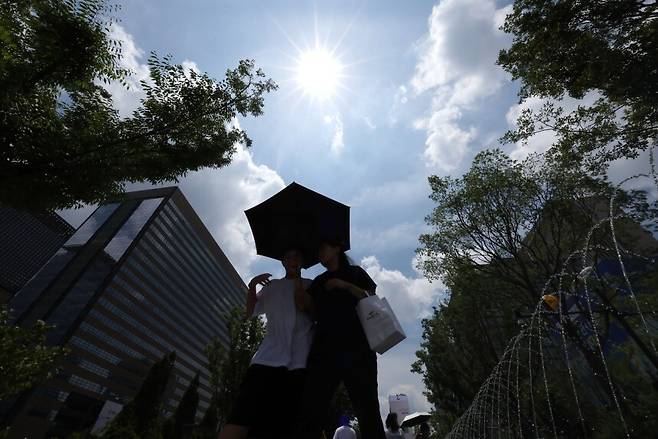 서울 광화문광장에서 시민들이 양산을 쓰고 걸어가고 있다. 연합뉴스