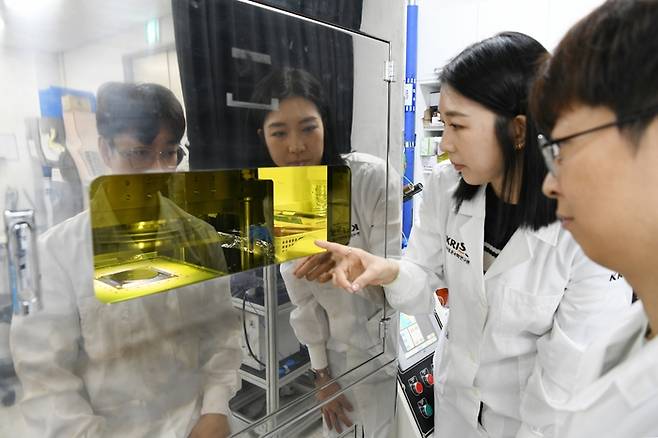 이은숙 박사후연구원(좌)과 이진형 박사후연구원(우)이 나노 디스크 합성을 위한 임프린팅 장비를 관측하고 있다.