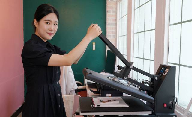 ▲이주원 대표가 패브릭 소품에 로고를 인쇄하고 있다.