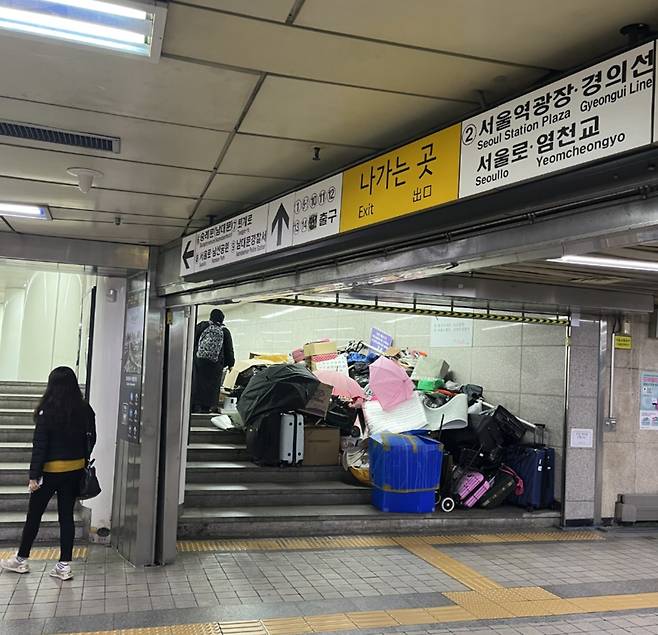 A 할머니는 지하철역과 통행로 사이 계단에 박스와 우산, 캐리어 등으로 성인 허리춤 높이 자신만의 요새를 지어 생활하고 있는데, 워낙 짐이 많은 터라 거의 마지막으로 자리를 벗어났다. 할머니는 청소 작업에 동원된 관계자들을 향해 한때 언성을 높였다. 시민들은 큰 소리에 궁금한 듯 발걸음을 멈추고 현장을 기웃거리나 쳐다보며 지나갔다./사진=독자 제공.