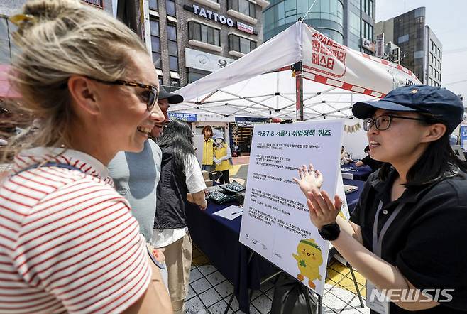 [서울=뉴시스] 정병혁 기자 = 17일 서울 마포구 홍대 레드로드에서 열린 2024 레드로드 청년 일자리 페스타를 찾은 시민들이 서울시 취업정책 퀴즈를 풀고 있다. 2024.05.17. jhope@newsis.com