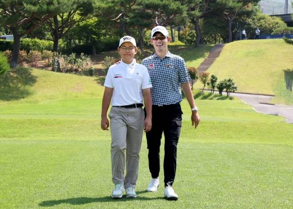 김비오(오른쪽)가 18일 경남 양산 에이원CC에서 열린 한국프로골프(KPGA) 선수권대회 연습 라운드 도중 골프 꿈나무 김세준군과 일부 홀을 함께 돌며 환하게 웃고 있다. KPGA 제공