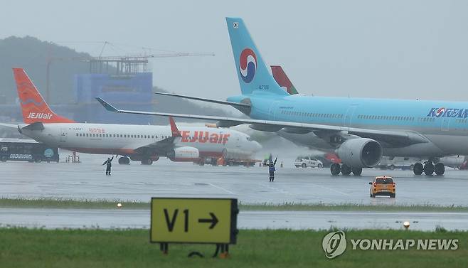 장맛비 내리는 제주국제공항 (제주=연합뉴스) 박지호 기자 = 장맛비가 내린 16일 오전 제주국제공항 계류장에서 우비를 쓴 지상조업원들이 작업하고 있다. 2025.6.16 jihopark@yna.co.kr