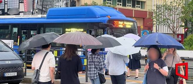 세종대로 사거리에서 우산을 쓰고 횡단보도를 건너는 직장인들. 이은서 기자.