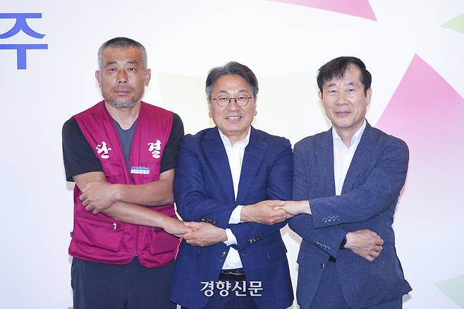 강기정 광주광역시장(가운데)이 20일 오전 시청 접견실에서 박상복 광주지역노조동조합 위원장(왼쪽), 임동춘 광주버스운송사업조합 이사장(오른쪽)과 시내버스 노사 임단협 합의서에 서명한 뒤 손을 맞잡고 있다. 광주광역시 제공