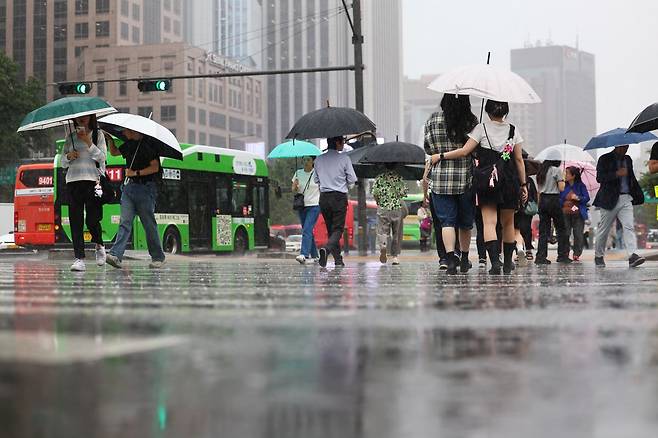 서울 전역에 호우주의보가 내린 20일 서울 종로구 광화문 네거리에서 우산을 쓴 시민들이 길을 건너고 있다. 연합뉴스