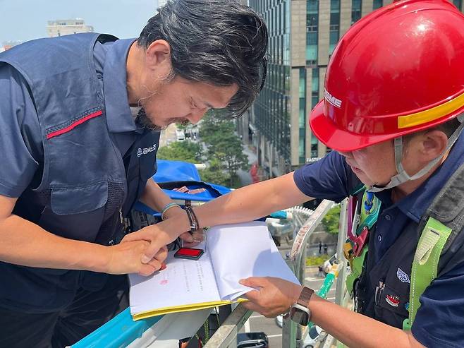 지난 6월 19일 서울 중구 한화 본사 앞 30미터 높이 철탑에서 김형수 거제통영고성 조선하청지회장이 하청 노사 합의로 이뤄진 단체협약안에 직인을 찍고 있다 (출처 : 금속노조)
