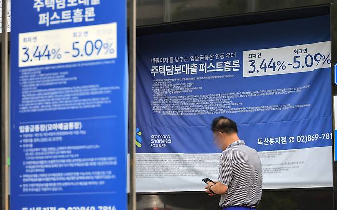 이달 들어 5대 은행(KB국민·신한·하나·우리·NH농협)의 가계대출 잔액이 4조원 넘게 불어난 것으로 나타났다. 사진은 서울 시내 은행 앞 대출 홍보물을 지나는 시민. [연합]