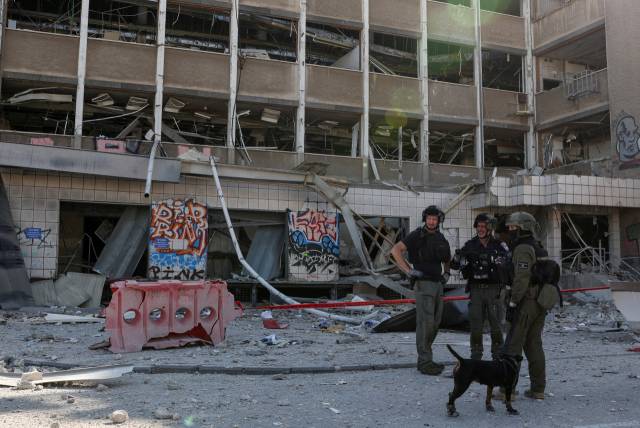 20일(현지 시간) 이스라엘 하이파 지역에서 이란의 미사일 공격을 받아 파괴된 건물 앞으로 구조대가 서있다. 로이터연합뉴스