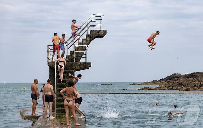 유럽 대륙에 때 이른 폭염이 찾아오며 프랑스 서부 일부 지역의 낮 최고 기온이 섭씨 38도, 체감온도는 40도를 기록한 가운데, 21일(현지시간) 프랑스 북서부 브르타뉴 지방의 생말로 해변을 찾은 시민들이 다이빙 등 해수욕을 하며 더위를 식히고 있다. 2025.6.22/뉴스1 ⓒ News1 이준성 기자