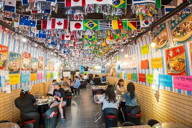 천장엔 만국기, 대나무 발 걸린 벽엔 손으로 쓴 메뉴판이 덕지덕지 붙어 있다. 스테인리스 쟁반 올린 드럼통 테이블까지. 얼핏 수십 년 된 포장마차처럼 보이지만 개업 반년 된 ‘뉴포’다. /김용재 영상미디어 기자