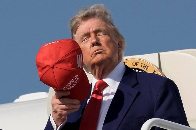 도널드 트럼프 미국 대통령이 21일(현지시간) 미국 메릴랜드주 앤드루스합동기지에 도착한 뒤 모자를 고쳐쓰고 있다. 연합뉴스