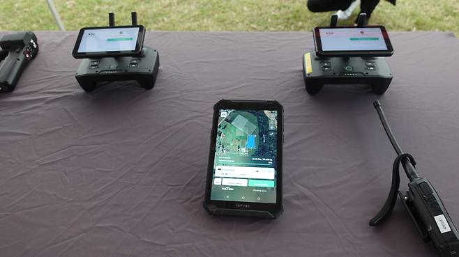 XAG오스트레일리아 드론을 조종하기 위한 스틱과 작업 상황을 보여주는 태블릿.