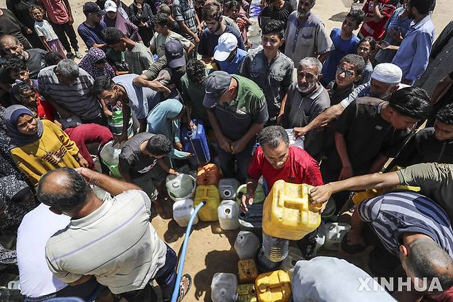 [가자시티=신화/뉴시스] 16일(현지 시간) 전쟁으로 물 부족 사태가 이어지고 있는 가자지구 가자시티 천막촌 근처에서 팔레스타인 피란민들이 식수를 받고 있다. 이스라엘군은 주말인 21일에도 가자 전체에 폭격을 가해 41명의 사망자와 수 백명의 부상자를 냈다.  2025.06.22.