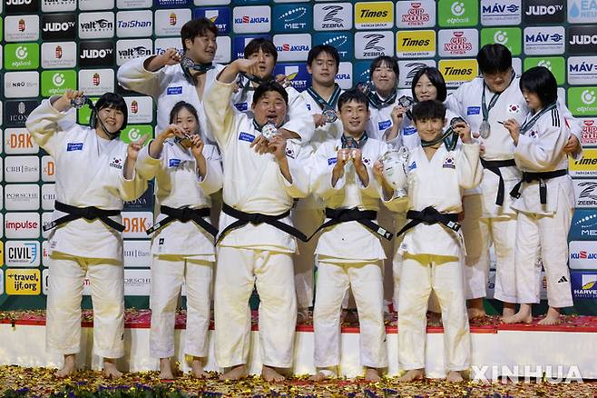 [부다페스트=신화/뉴시스] 한국 유도 대표 선수들이 지난 20일(현지 시간) 헝가리 부다페스트에서 열린 2025 국제유도연맹(IJF) 세계유도선수권대회 혼성 단체전에서 은메달을 따낸 후 메달을 들고 시상대에 올라 기념 촬영을 하고 있다. 한국은 결승전에서 조지아에 1-4로 패해 은메달을 따내면서 혼성 단체전 역대 최고 성적을 기록했다. 2025.06.22.