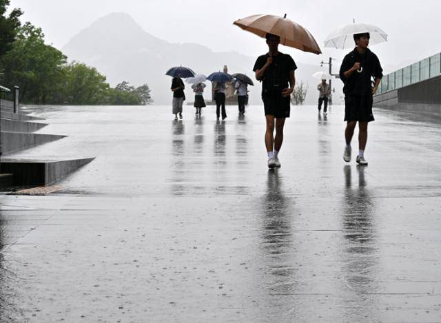 장마가 시작되며 서울 전역에 호우주의보가 내려진 20일 서울 종로구 광화문광장에서 시민들이 우산을 쓴 채 이동하고 있다. 홍인기 기자
