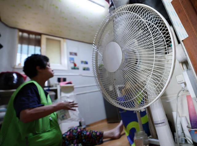 23일 서울 영등포구 쪽방촌에서 한 주민이 선풍기로 더위를 식히고 있다. 뉴스1