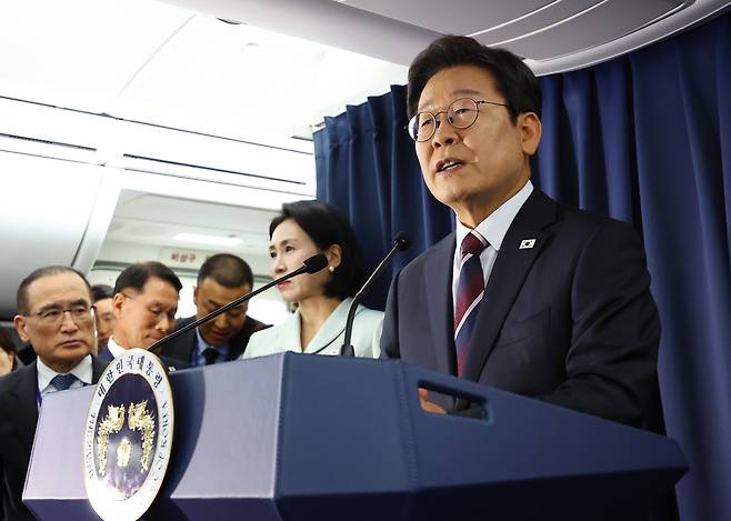 President Lee Jae Myung (right) speaks with reporters on June 16 while boarding the Air Force One, while en route to Canada to attend the Group of Seven summit. (Yonhap)
