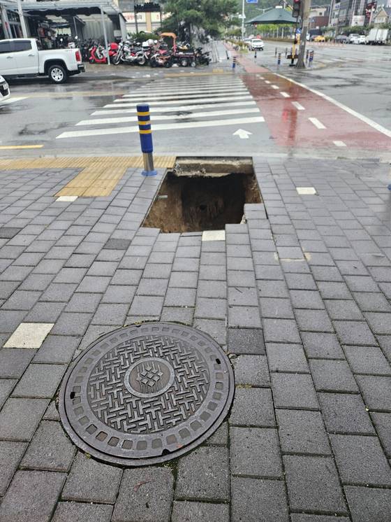 A sinkhole lies open on a sidewalk near a crosswalk in Dotong-dong in Namwon, North Jeolla, on June 21. [PARK]