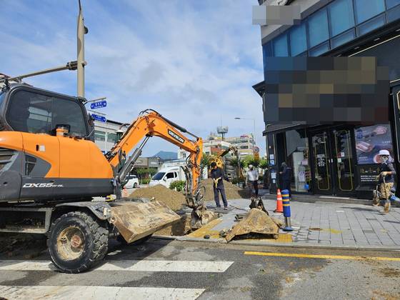 The Namwon city government conducts emergency repairs using an excavator and personnel in front of a restaurant in Dotong-dong, on June 22. [PARK]
