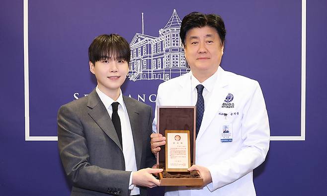 방탄소년단 슈가(왼쪽)가 지난 4월 연세의료원 종합관에서 50억원 기부에 대한 감사패를 받은 후 금기창 연세의료원장과 기념촬영을 하고 있다. 세브란스병원 제공