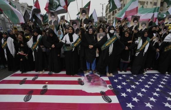 22일(현지시간) 파키스탄 카라치에서 이란에 대한 이스라엘의 공습을 비난하는 집회에 참석한 시아파 무슬림들이 미국 국기 위에 서 있다.  AP 연합뉴스