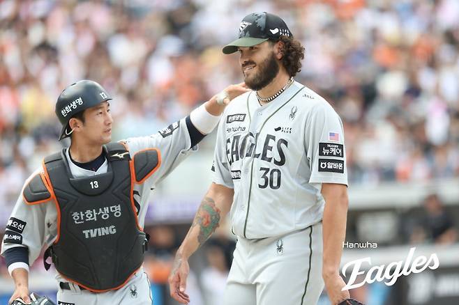 한화 코디 폰세(오른쪽)가 22일 대전 한화생명이글파크에서 열린 키움전에서 3회초를 마친 뒤 덕아웃으로 향하며 포수 최재훈으로부터 격려를 받고 있다. 폰세는 이날 피치클락 지연 경고로 시작된 상황으로 인해 3회초 도중 키움 타자 임지열과 설전을 벌였다. 사진제공｜한화 이글스