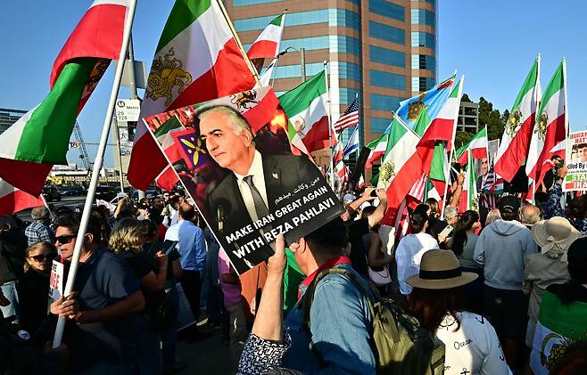 시위대가 23일 미국 로스앤젤레스연방 건물 밖에서 이란 정권 교체를 촉구하며 레자 파흘라비 포스터를 흔들고 있다. /연합뉴스