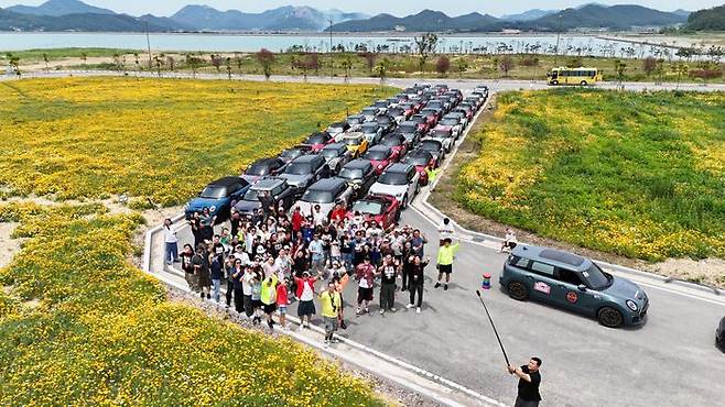 자로 잰듯 반듯하게 정렬된 차량들 앞으로 참가자들이 단체 사진을 촬영하고 있다. 이 사진을 한 장을 찍기 위해 운영진들은 주차 가능한 장소를 수개월 전 미리 물색하고, 당일 수십대의 차량을 직접 통제한다.ⓒ미니코리아