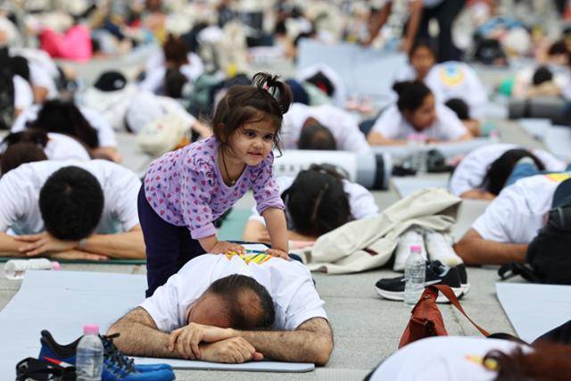 21일 서울 종로구 광화문광장에서 열린 제11회 UN 세계요가의 날 행사에서 한 어린이가 요가하는 참가자들을 구경하고 있다. 연합뉴스