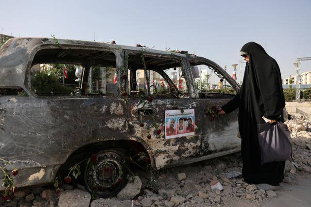 한 이란 여성이 23일 이란 수도 테헤란에서 폭격을 맞은 차량을 바라보고 있다. 테헤란=로이터 연합뉴스