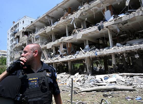 지난 21일 이스라엘 중심 도시 텔아비브에서 이란의 탄도미사일 공격으로 파괴된 건물 잔해를 바라보며 이스라엘 경찰이 괴로운 표정을 짓고 있다. [UPI=연합뉴스]
