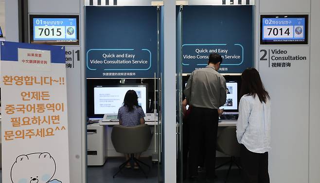 신한은행 독산동 외국인 특화 점포에 통역 도움 관련 입간판이 설치돼 있다. 그 안쪽으로 점포를 찾은 고객들이 업무를 보고 있다. [이승환 기자]