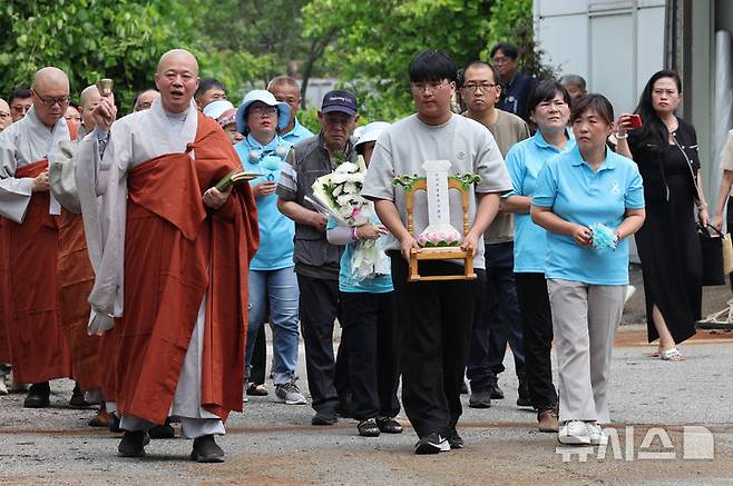 [화성=뉴시스] 김종택 기자 = 24일 오전 경기 화성시 전곡리 아리셀 참사 화재현장에서 열린 '아리셀 참사 1주기 현장 추모 위령제'에서 유가족들이 위패를 들고 이동하고 있다. (공동취재) 2025.06.24. photo@newsis.com