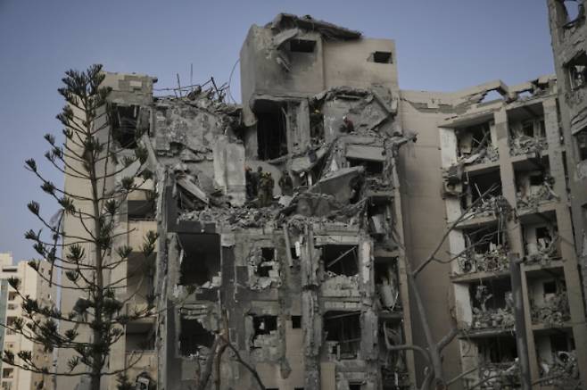 24일(현지시간) 이스라엘 남부 베르셰바에서 이스라엘 군인과 구조대가 이란의 미사일 공격으로 파괴된 주거 건물 잔해를 수색하고 있다. 연합뉴스