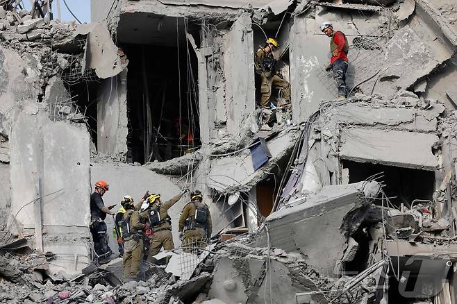 24일(현지시간) 이스라엘 남부 베르셰바에서 이란의 미사일 공격으로 파괴된 건물을 긴급 구조대원들이 점검하고 있다. 2025.06.24 ⓒ AFP=뉴스1 ⓒ News1 송송이 기자