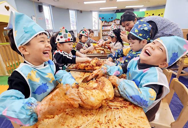 Children smile while making kimchi at their day care center in Gwangju in December 2023. [YONHAP]
