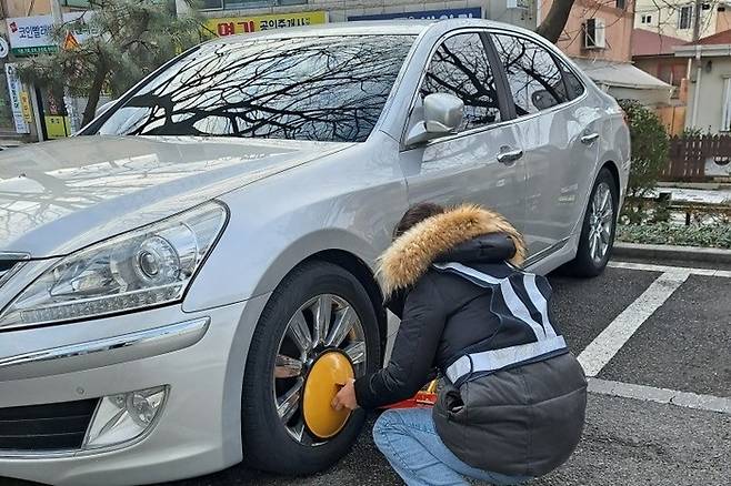 지방세 체납 단속반이 체납 차량에 족쇄를 채우고 있다. <자료=울산 남구>