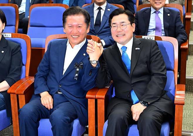 더불어민주당 당대표 선거에 출마한 정청래(왼쪽)·박찬대 의원이 24일 오후 서울 여의도 국회에서 열린 의원총회에 참석해 자리에 앉아 손을 맞잡고 있다.  이상섭 기자