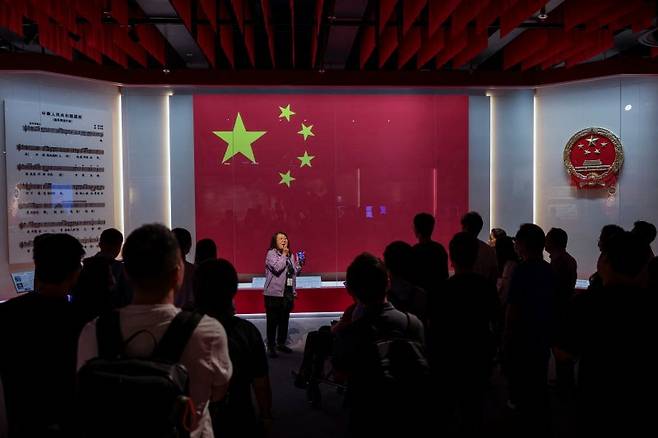 중국 홍콩에서 열린 국가보안법 5주년을 앞두고 20일 국가보안전시관에서 한 가이드가 중국 국기와 엠블럼 앞에서 방문객들에게 설명하고 있다. 로이터 연합뉴스