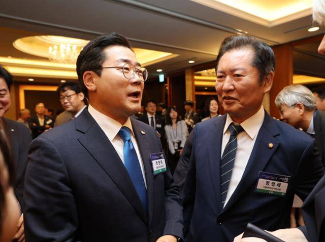 더불어민주당 당대표 선거에 출마한 박찬대(왼쪽) 의원과 정청래 의원이 25일 서울 중구 롯데호텔에서 열린 2025 경향포럼에 참석해 인사하고 있다. 뉴시스