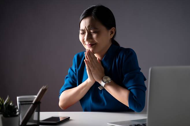장준식 미국 세화교회 목사는 “자본주의에 잠식된 언어로 기도하기보단 그리스도의 말씀과 서사, 일상이 담긴 언어로 기도할 것”을 권한다. 사진은 한 여성이 직장에서 인상을 쓴 채 손 모아 기도하는 모습. 게티이미지뱅크