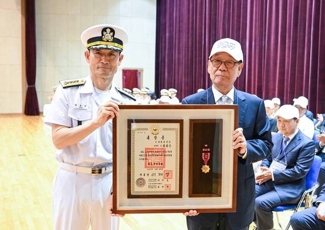 26일 충남 계룡대 해군본부에서 거행된 6·25전쟁 무공훈장 서훈식에서 양용모(왼쪽) 해군참모총장이 대한청년단 고(故) 김갑순 단원의 아들인 김상태(오른쪽)씨에게 화랑무공훈장을 전도 수여하고 있다. 해군 제공