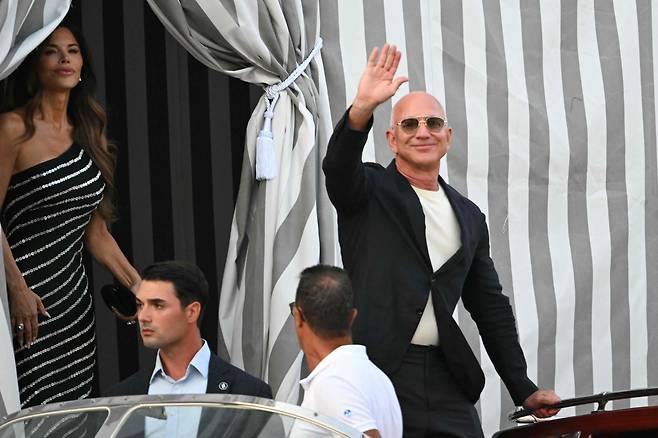 25일(현지시간) 이탈리아 베네치아에서 아마존 창업자 제프 베이조스(오른쪽)과 그의 약혼자 로렌 산체스가 호텔을 떠나고 있다. [AFP]