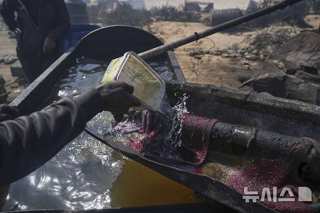 [가자시티=AP/뉴시스] 지난 22일(현지 시간) 가자지구 가자시티 남쪽 시로드에서 팔레스타인인이 플라스틱에서 추출한 연료를 식히기 위해 물을 사용하고 있다. 팔레스타인 청년들은 플라스틱 폐기물을 금속 드럼에 넣고 가열해 만든 연료를 병에 담아 판매하며, 이는 현지에서 발전기나 이동용 연료로 사용된다. 유독한 연기와 불길에 노출되는 고된 작업이지만, 이들에게는 가족의 생계를 이어가는 거의 유일한 수단이다. 2025.06.25.<font style="vertical-align: inherit;"><font style="vertical-align: inherit;"></font></font>